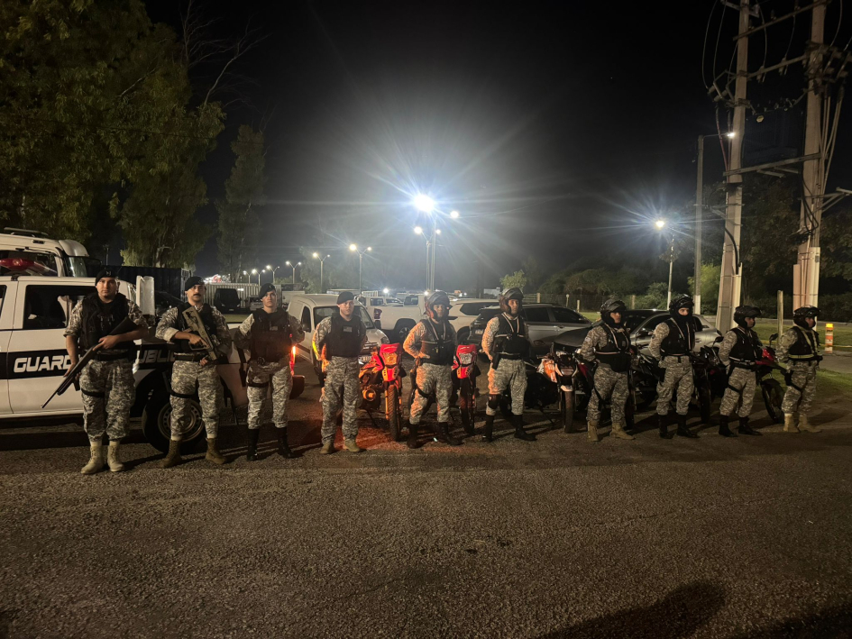 Policías de la Guardia Republicana formados con motos y móviles, en la noche.