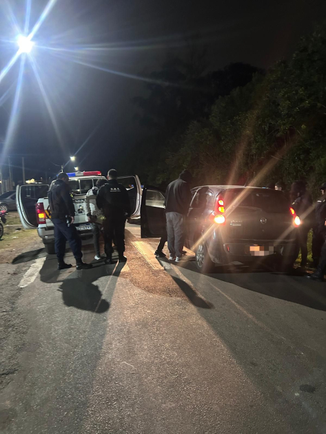Funcionarios policiales trabajan junto a vehículo interceptado durante operativo nocturno.