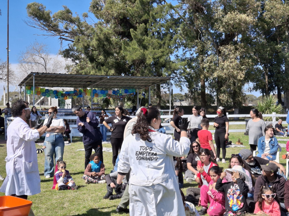 Animadores de ECO Circo Social con batas blancas interactúan con el público reunido en un parque