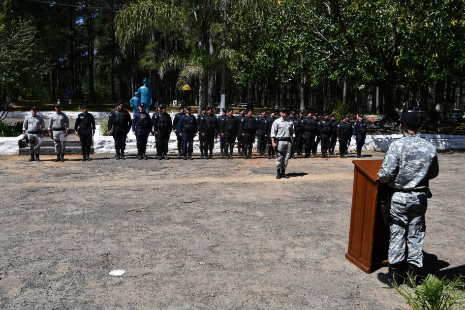 Un oficial DNGR da un discurso desde un podio a una formación de policías uniformados de azul.