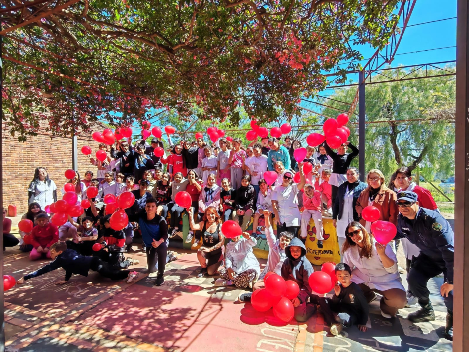 Foto grupal de niños, docentes y funcionarios participantes con globos rojos Foto grupal de niños, docentes y funcionarios participantes con globos rojos