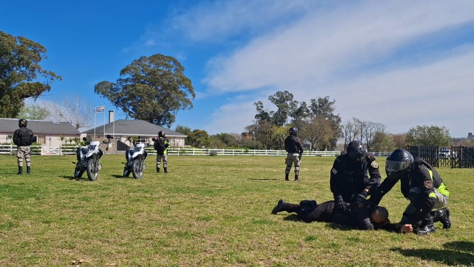 Demostración de intervención policial Policias interviniendo en una escena, asistiendo a un lesionado y al fondo dos motos con custodia