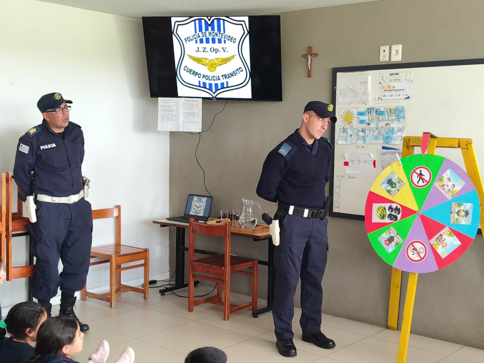 Instructores de Policía de Tránsito imparten educación vial en la Fundación Los Pinos Policía parado de frente a niños explicando la importancia de la seguridad vial