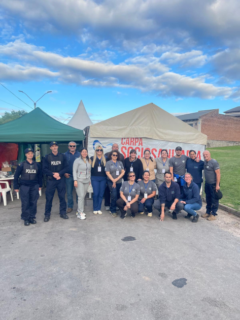 Personal policial y equipos de asistencia reunidos frente a la carpa sociosanitaria.