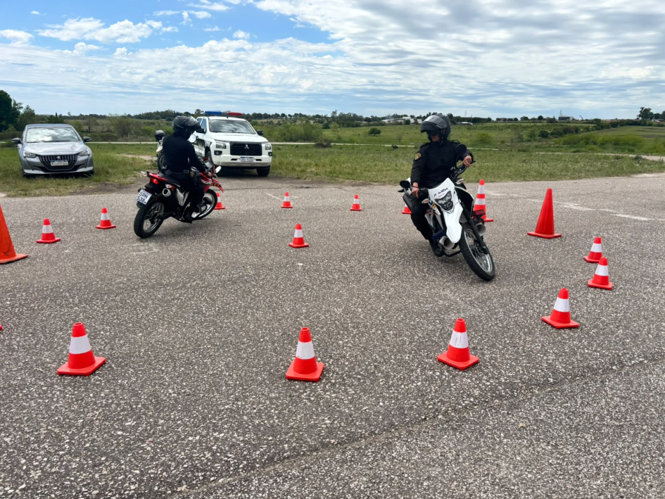 Dos policías realizan maniobras en motocicleta en un circuito circular delimitado por conos naranja.