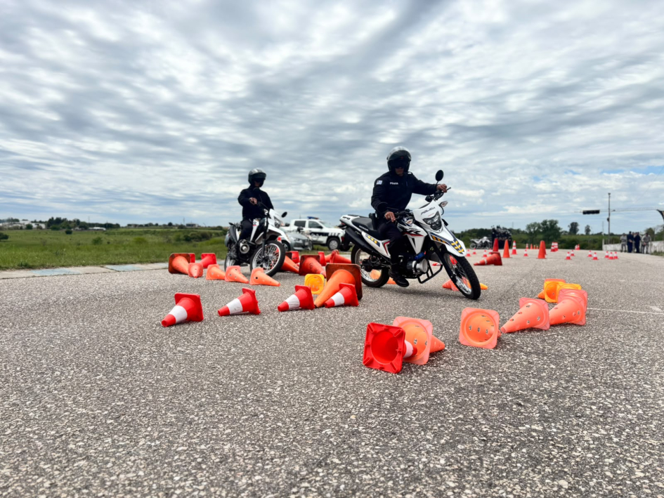 Agentes en motos de la Policía esquivan un circuito de conos anaranjados en pista asfaltada.