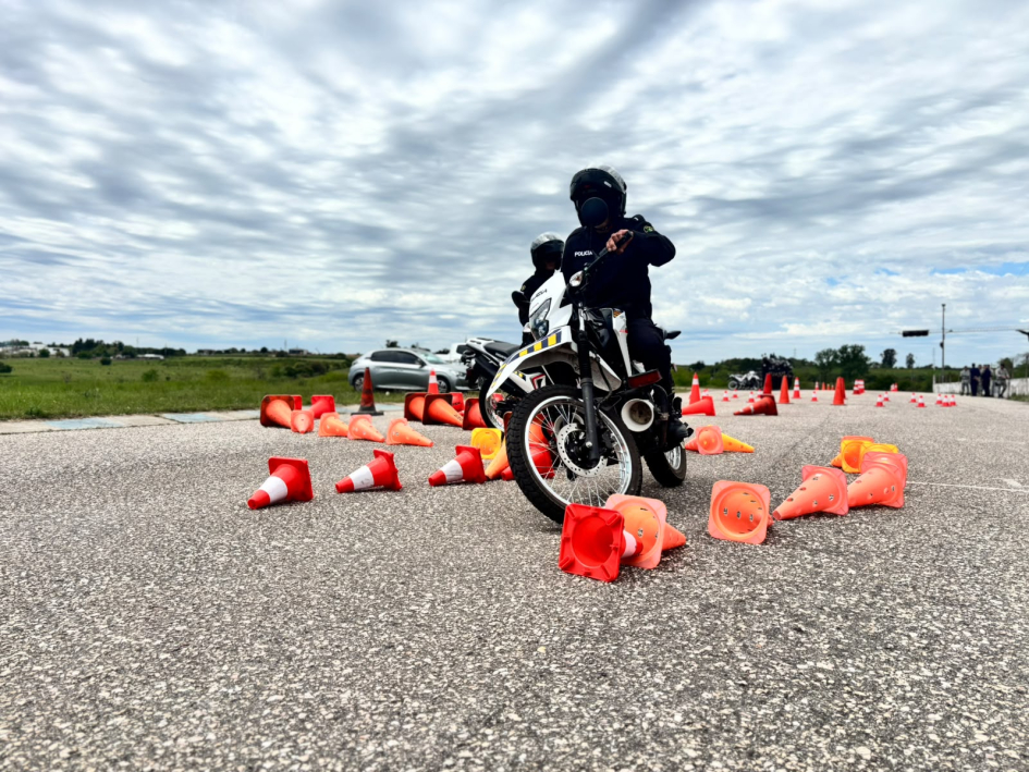 Policía conduce entre conos naranjas durante una prueba de precisión y control con motocicleta.