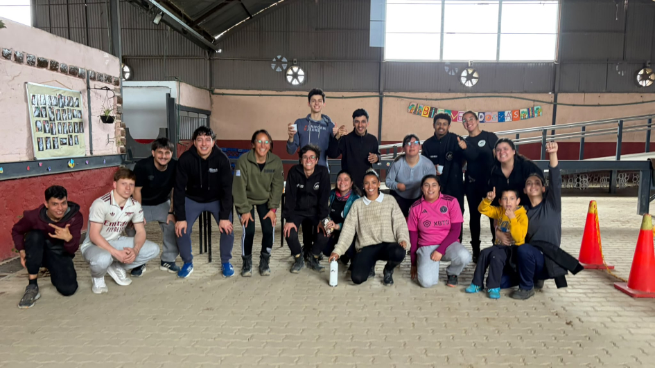 Visita de alumnos de ISEF a la DNGR Grupo de alumnos y profesores posando sonrientes dentro de la pista de equinoterapia