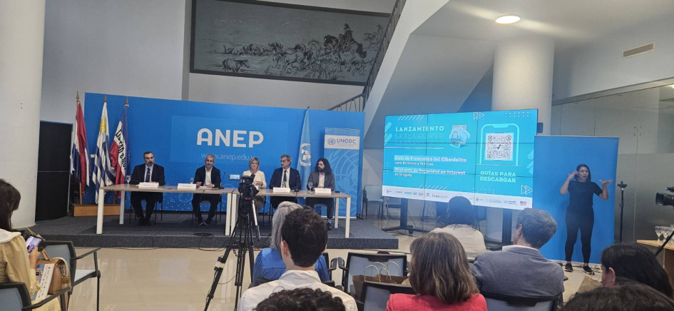 Autoridades de ANEP, Fiscalía, Ministerio del Interior, Naciones Unidas y Embajada de Estados Unidos 5 personas al frente del público en un estrado