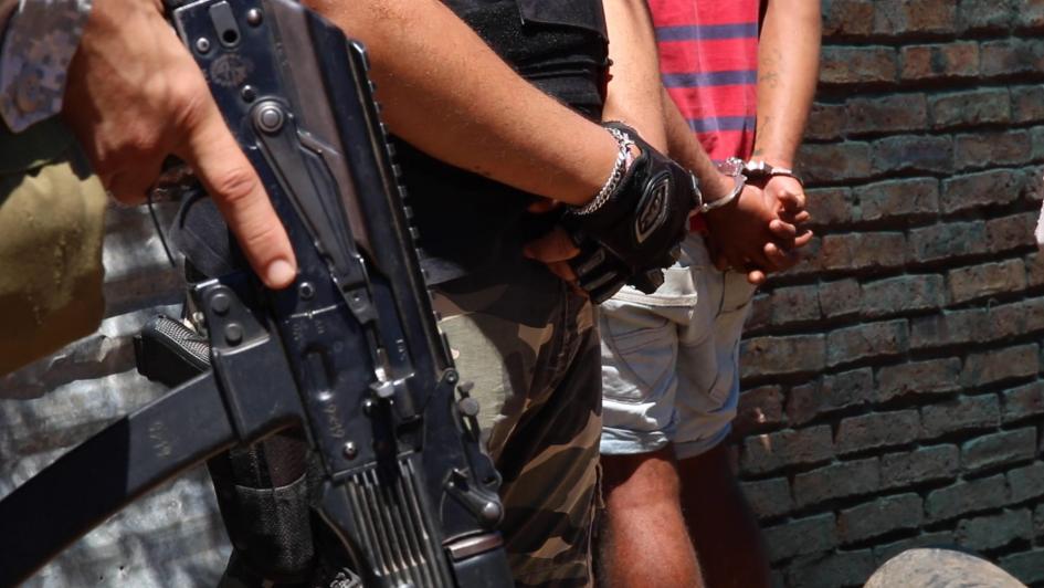 Formlizado por Homicidio en San Carlos Hombre parado con las manos esposadas atrás y dos policías parados al lado uno de ellos un con arma
