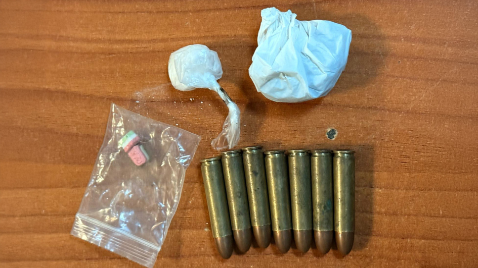 Municiones y pequeños envoltorios con presuntas drogas sobre una superficie de madera. Municiones y pequeños envoltorios con presuntas drogas sobre una superficie de madera.