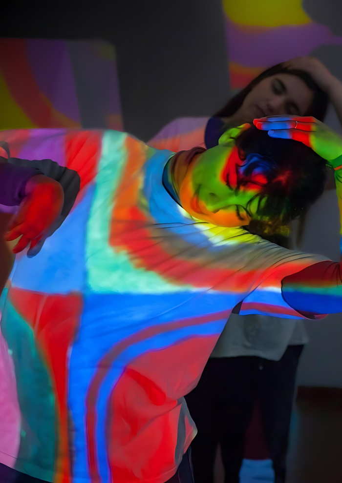 Joven baila mientras su cuerpo es iluminado por proyecciones de diseños abstractos