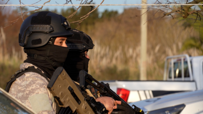 Dos policías con equipo táctico armados con cascos y pasamontañas durante un operativo de campo
