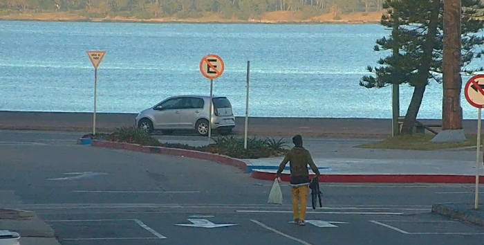 un hombre caminando en la calle llevando ruedas de bicicleta en la mano