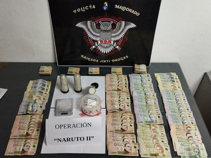 sobre una mesa se exhiben: tarros con droga y dinero incautado tras operativo policial