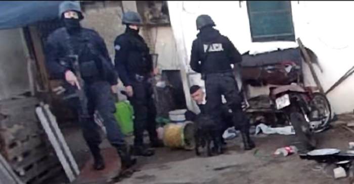 Detenido en boca de drogas detenido sentado en el piso al lado de una moto con tres policias de negro