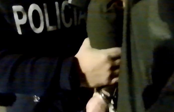 Detenido esposado siendo llevado por un policía Detenido esposado siendo llevado por un policía