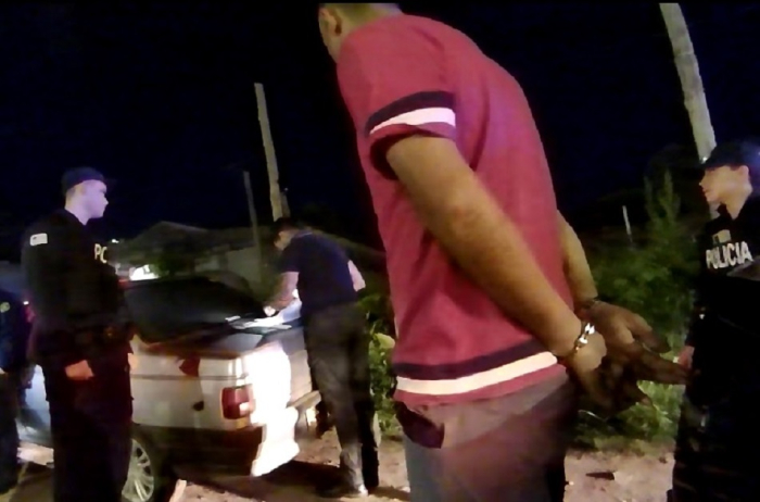 Detenido esposado siendo llevado por un policía Detenido esposado siendo llevado por un policía