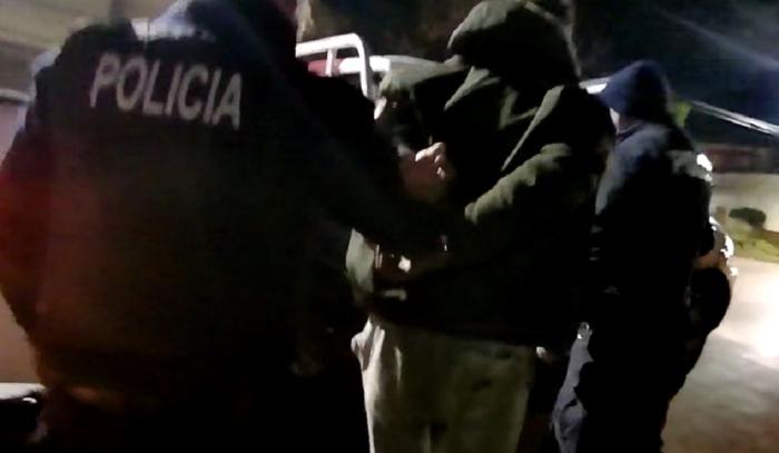 Detenido esposado a la espalda llevado por un policía
