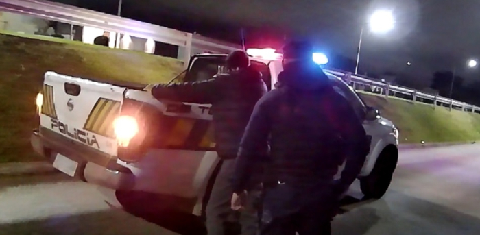 móvil policial con detenido y policía de espalda