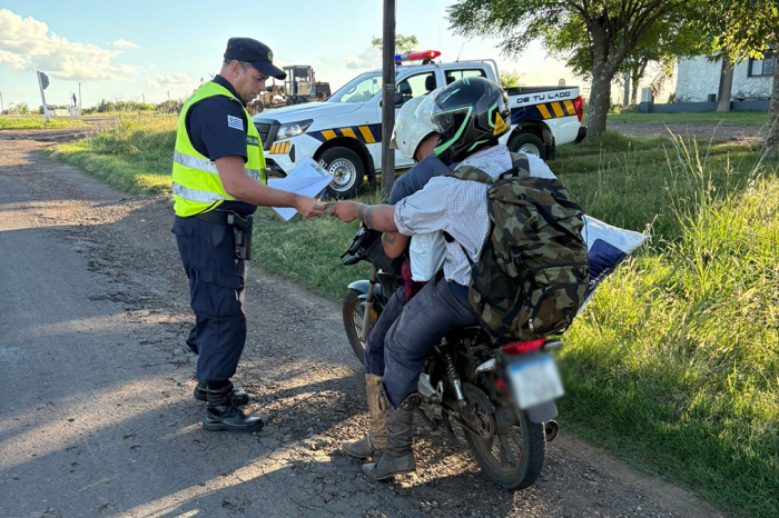 Dos personas en motocicleta siendo inspeccionados por un policía