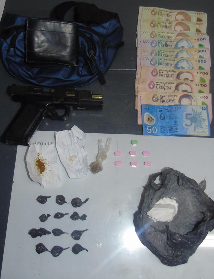 arma de aire comprimido, droga y dinero incautados, se exhiben sobre una mesa 