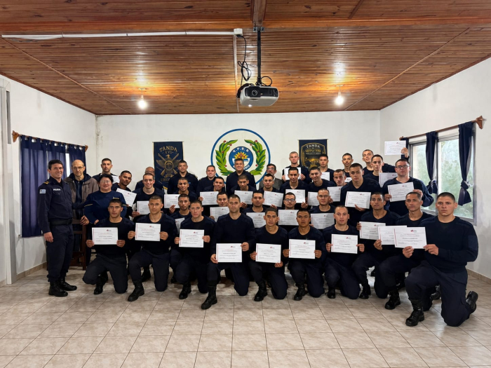Jefe de Policia Crio Gral (R) Williams Garcia, autoridades y alumnos de formacion policial un salon con un grupo de personas en semicirculo, algunas paradas y otras semi flexionadas