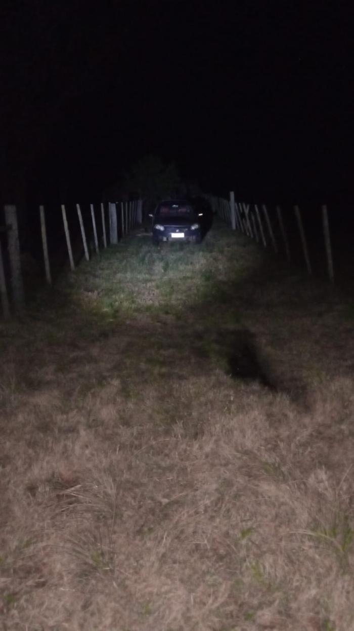 Vehículo entre dos alambrados alumbrado desde lejos por la policía Vehículo entre dos alambrados alumbrado desde lejos