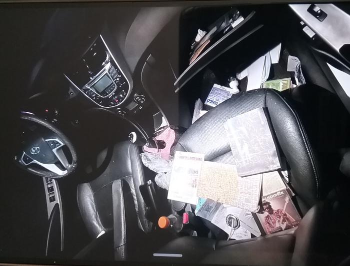 interior de un auto, con papeles y objetos tirados sobre los asientos 