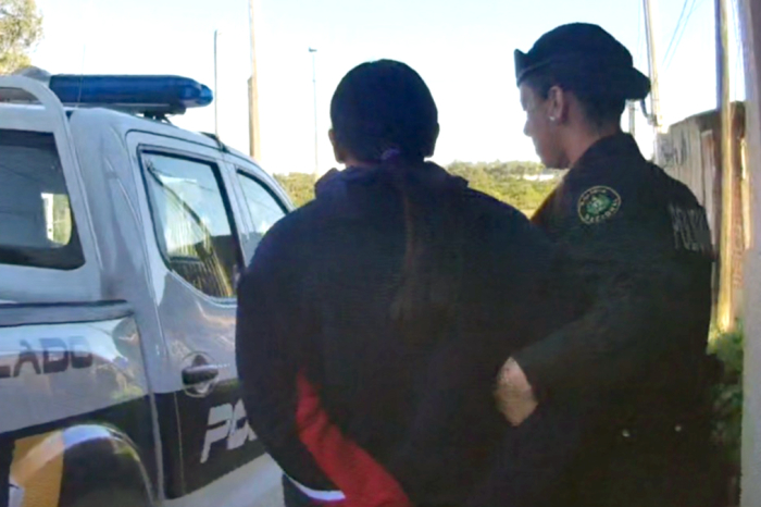 Mujer requerida siendo llevada por la policia.