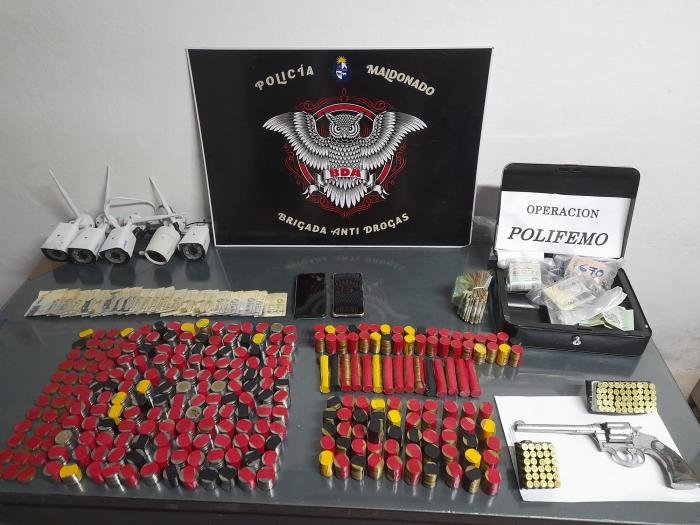 exhibición de dinero, cámaras de vigilancia, celulares, arma y municiones incautadas