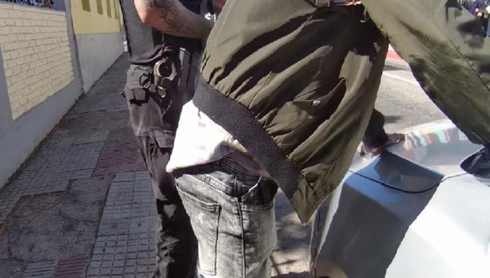 Persona detenida con manos apoyadas en patrullero