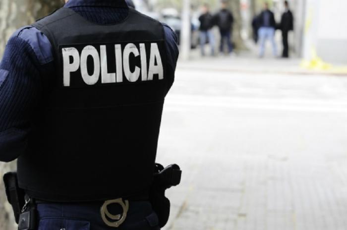 Policía de espalda y detenidos al fondo lejos