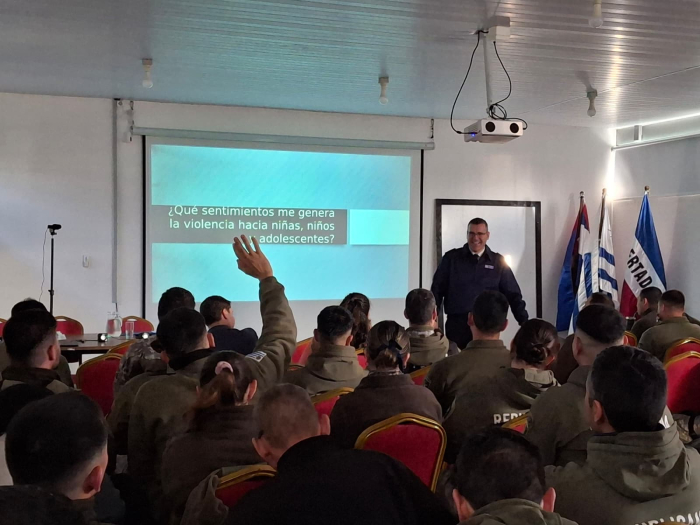 Policías uniformados en sala de conferencias, uno levanta la mano para hacer una pregunta.