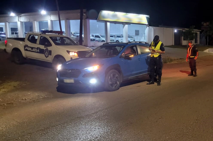 Un automovil con ocupante en control policial Un automovil azul con un ocupante y dos policías controlando
