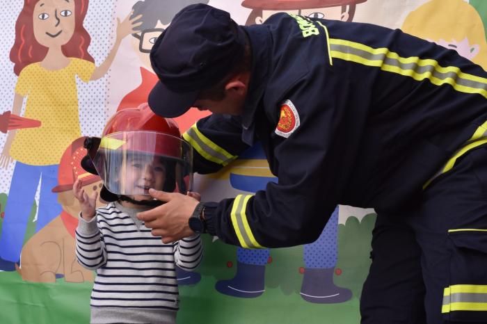 Bombero ayudando a niño a ponerse casco para la foto.