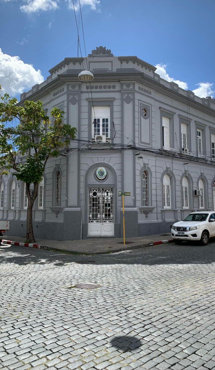 Fachada del edificio del Área de Investigaciones en Mercedes, esquina adoquinada y cielo despejado