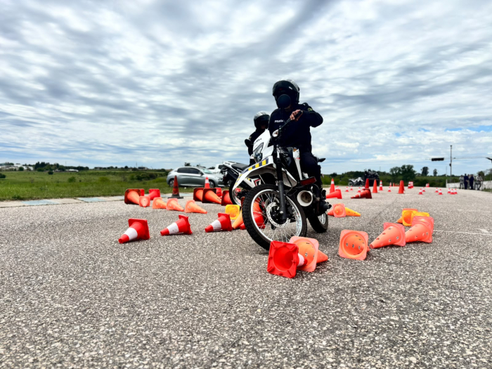 Policía conduce entre conos naranjas durante una prueba de precisión y control con motocicleta.
