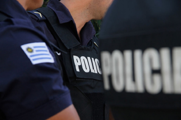 Imagen ilustrativa insigneas de policía y bandera de Uruguay en brazo y espalda de efectivos policiales