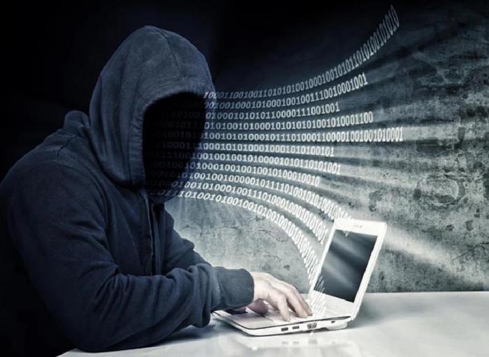 Estafador con capucha frente a una notebook