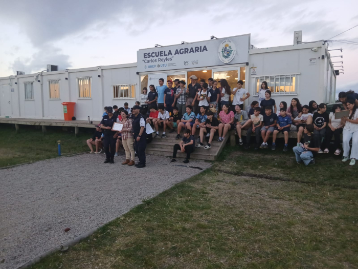 Niños sentados frente a la escuela Agraria Carlos Reyles junto a la Policía Comunitaria entregando c Niños sentados frente a la escuela Agraria Carlos Reyles junto a la Policía Comunitaria entregando c