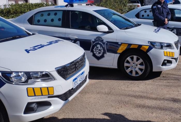Dos móviles policiales estacionados y un policía parado al costado