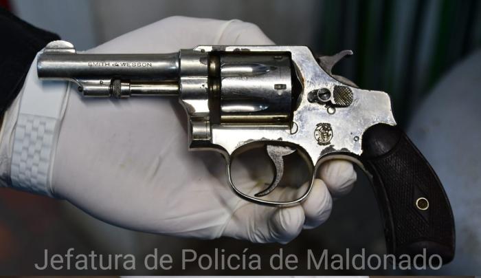se ve la mano de una persona con guante sosteniendo un arma 