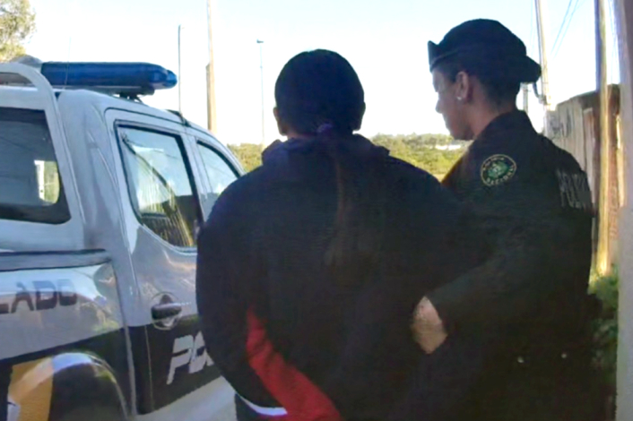 Mujer requerida siendo llevada por la policia.