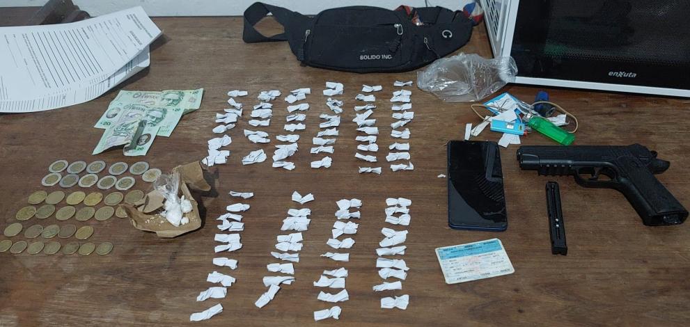 Se observan los objetos incautados: pistola de aire comprimido y 100 envoltorios con cocaina