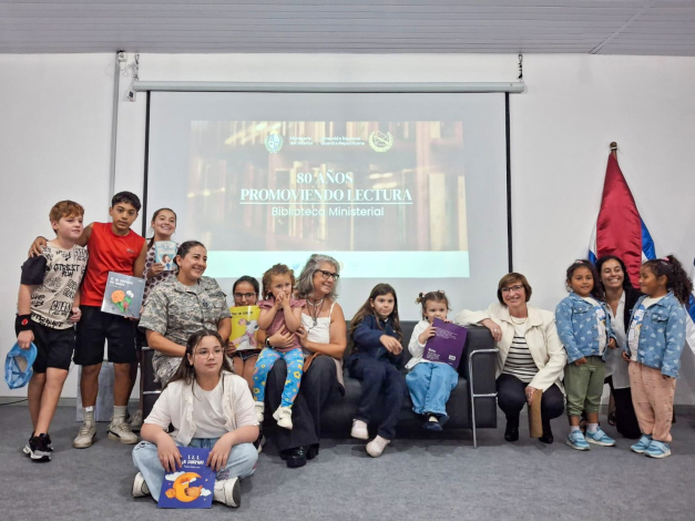 Foto grupal de Directora DNGR, Biblioteca, autora infantil, niñas y niños en sala de conferencia