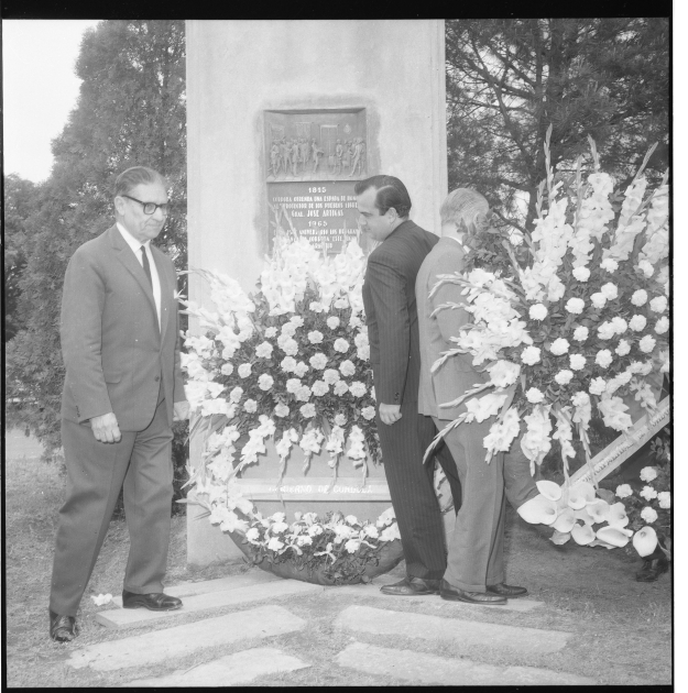Fotografía de la placa y las ofrendas florales colocadas al pie del monumento.