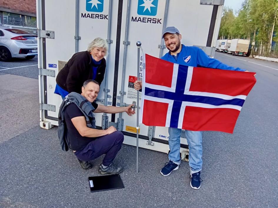 Members of the Hjelpemiddelfondet organization Members of the organization at the door of the already loaded container hold the Norwegian flag