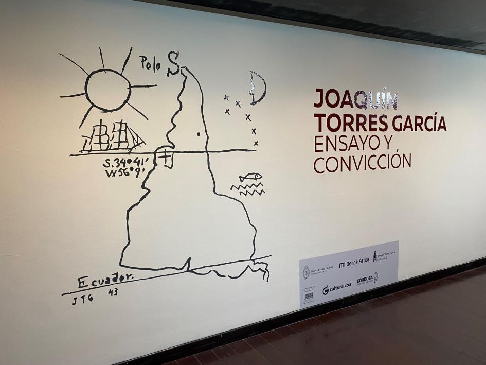 Afiche de recepción a la muestra Foto del afiche de la muestra con el dibujo de América del Sur con el Sur en la parte superior