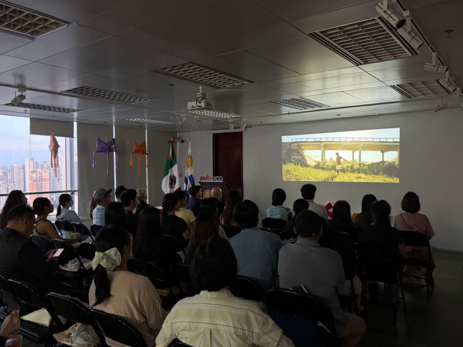Foto tomada desde ángulo derecho de la sala, con la pantalla de fondo proyectando la película